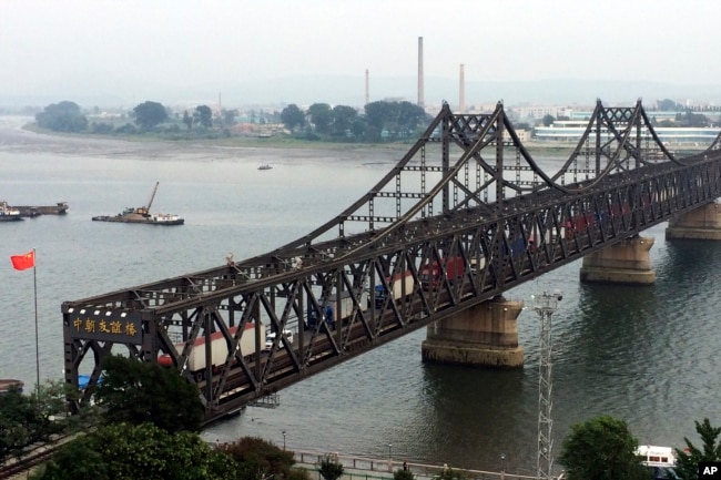 FILE - Trucks cross the friendship bridge connecting China and North Korea in the Chinese border town of Dandong, opposite the North Korean town of Sinuiju, Sept. 4, 2017.