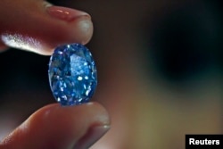An employee holds a 10.10-carat internally flawless blue diamond at Sotheby's auction house in London, March 15, 2016.