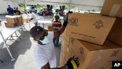 City worker Randy Greice, foreground, unloads a pallet of food at a food distribution event, Oct. 6, 2020, in Opa-locka, Florida.