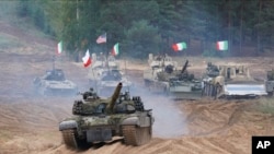 На цьому ілюстративному фото зображена військова техніка і танки Польщі, Італії, Канади та США під час військових навчань НАТО "Намейс 2021" на полігоні у Латвії, 13 вересня 2021 р. (Фото: AP Photo/Роман Коксаров)
