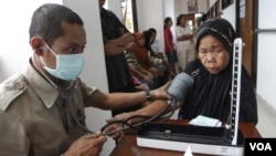 Petugas kesehatan memeriksa tekanan darah seorang pasien lanjut usia di sebuah Puskesmas di Jakarta. (Foto: dok). 