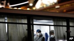 A bus carrying some European passengers from the quarantined Diamond Princess cruise ship leaves a port in Yokohama, near Tokyo, Feb. 21, 2020. Passengers tested negative for COVID-19 started disembarking Wednesday.