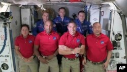 In this frame grab from NASA TV, SpaceX Dragon crew, from front left to right, Shannon Walker, Victor Glover, Mike Hopkins and Soichi Noguchi stand with International Space Station crew Kate Rubins, from back left, Expedition 64 commander Sergey Ryzhikov 
