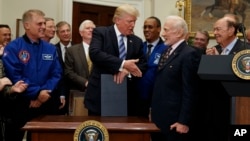 President Donald Trump shakes hands with former astronaut Buzz Aldrin after signing an executive order to establish a National Space Council, June 30, 2017, in the Roosevelt Room of the White House in Washington. 