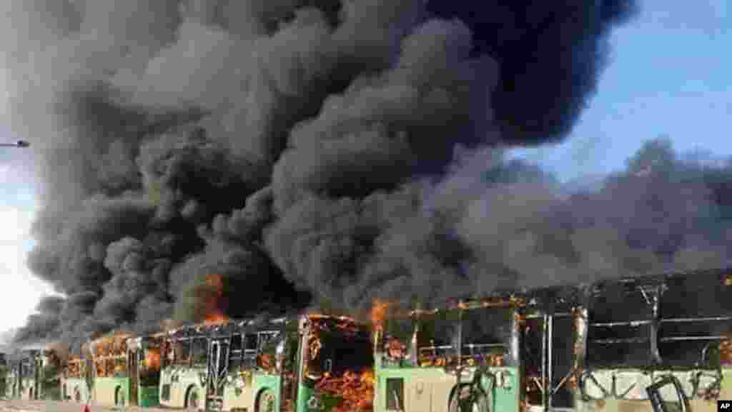 In this photo released by the Syrian official news agency SANA, smoke rises in green government buses, in Idlib province, Dec. 18, 2016. Activists said, militants have burned at least five buses assigned to evacuate wounded and sick people from two villages in northern Syria.