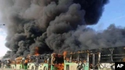 In this photo released by the Syrian official news agency SANA, smoke rises in green government buses, in Idlib province, Syria, Dec. 18, 2016. 