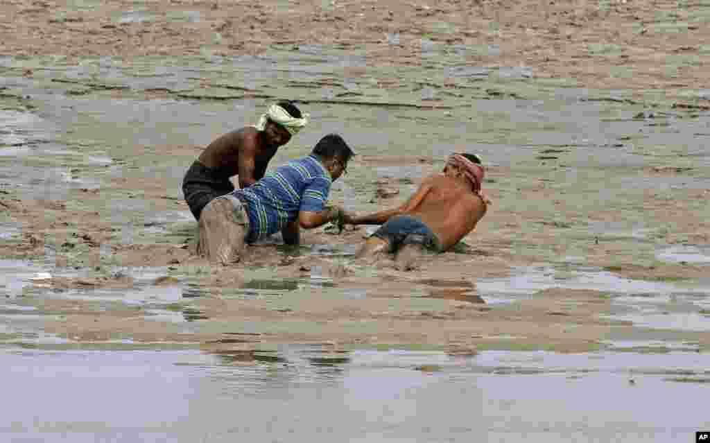 Indian boatmen pull out a man trapped in a swamp after heavy rainfall at Sangam in Allahabad.