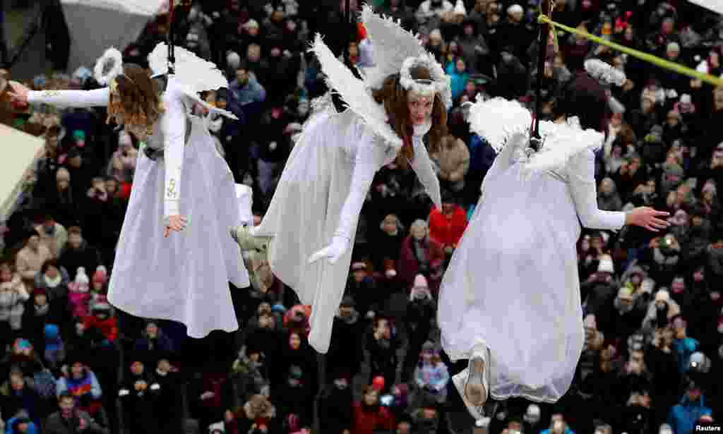 Women dressed as angels wave to spectators as they hang from a wire during a Christmas market in the town of Ustek, Czech Republic, Dec. 15, 2018.