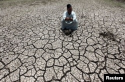 An Egyptian farmer squats down on cracked soil to show the dryness of the land due to drought in a farm formerly irrigated by the river Nile, in Al-Dakahlya, about 120 km from Cairo, June 4, 2013.