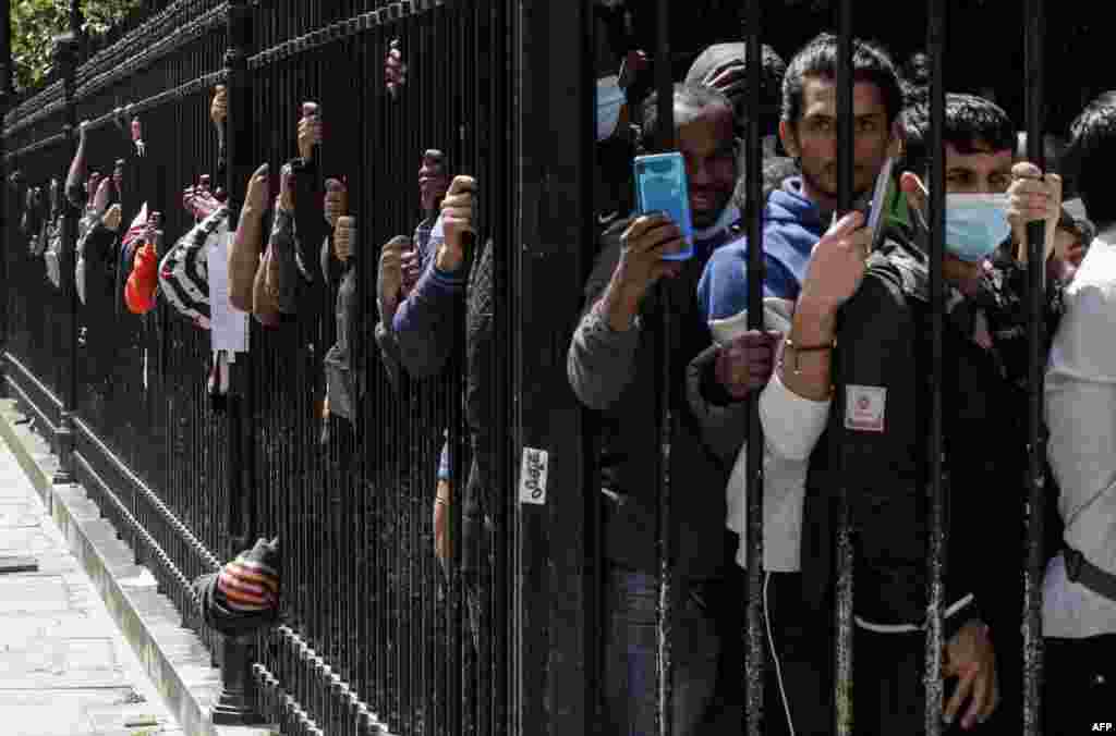 Migrants and homeless people wait behind the fences of the Place des Vosges in Paris, to be relocated after spending the night in tents installed the day before during an action organized by the Utopia association to ask for housing.