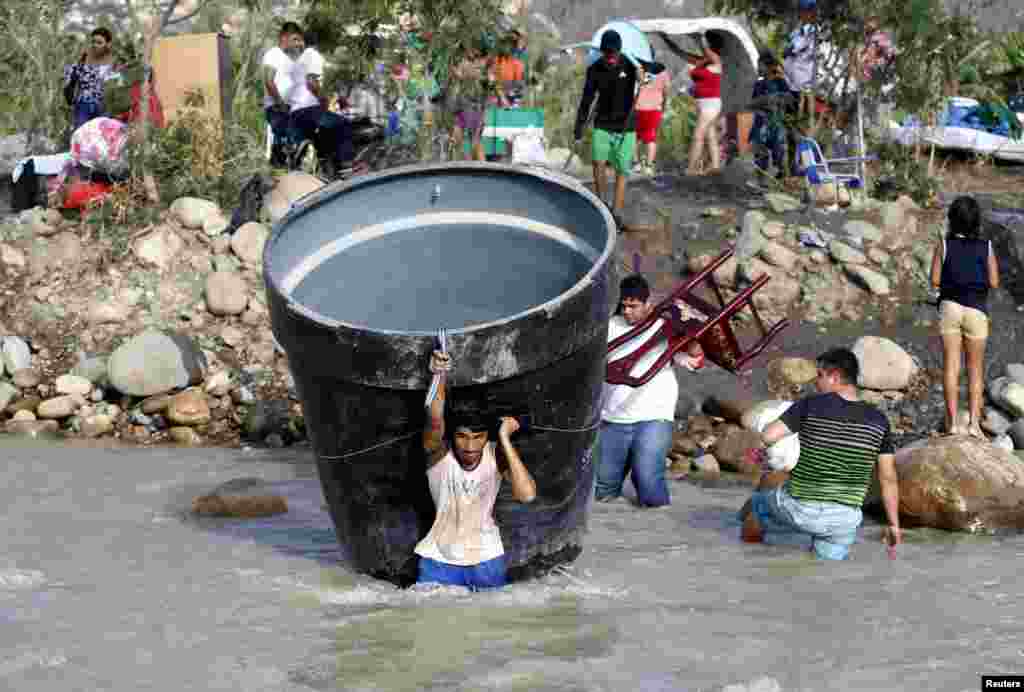 People carry their belongings while crossing the Tachira river border with Venezuela into Colombia, near Villa del Rosario village, Aug. 25, 2015.