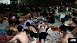 In this photo taken on Feb. 23, 2025, alleged scam center workers and victims rest during a crackdown operation by the Karen Border Guard Force (BGF) on illicit activity, at the border checkpoint with Thailand in Myanmar's eastern Myawaddy township.