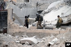 FILE - Iraqi security forces, supported by U.S.-led coalition airstrikes, advance their position through damaged buildings toward central Ramadi, Dec. 24, 2015. Rebuilding is crucial to keep control of the city.