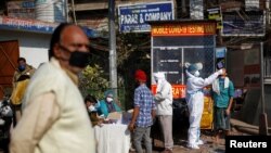 A healthcare worker wearing personal protective equipment (PPE) collects a swab sample from a man, amidst the spread of the coronavirus disease (COVID-19), at market area in the old quarters of Delhi, India, Dec. 19, 2020. 