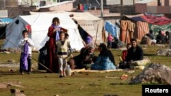 A Syrian refugee family sits in front of their makeshift tent in the town of Viransehir in Sanliurfa province, southeast Turkey, Feb. 10, 2013. 