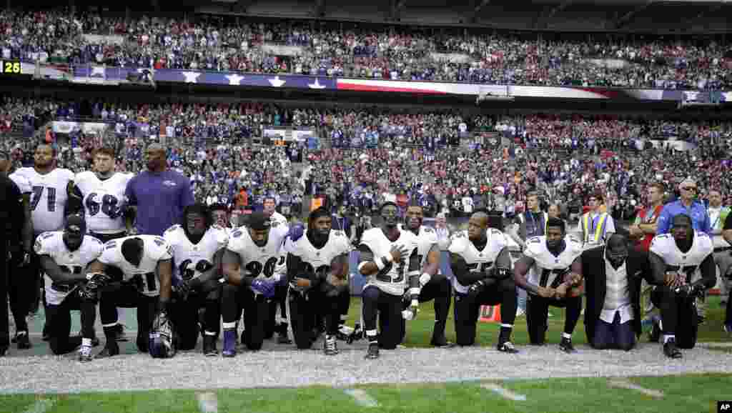 Baltimore Ravens players, including former player Ray Lewis, second from right, kneel down during the U.S. national anthem before an NFL football game against the Jacksonville Jaguars at Wembley Stadium in London.