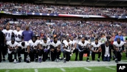 Beberapa atlet Baltimore Ravens saling bergandengan tangan ketika lagu kebangsaan dinyanyikan, sebagian berlutut dan sebagian lainnya berdiri, di London, Minggu (24/9).