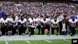 Baltimore Ravens players, including former player Ray Lewis, second from right, kneel down during the playing of the U.S. national anthem before an NFL football game against the Jacksonville Jaguars at Wembley Stadium in London, Sunday Sept. 24, 2017.