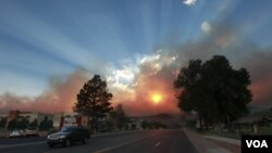 El sol se mira opacado por el humo que sale de las llamas que todavía persisten en Los Álamos, aunque los residentes de la ciudad podrán regresar a sus hogares.