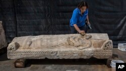 یکی از کارمندان اداره آثار باستانی و اشیای عتیقه اسرائیل در حال تمیز کردن تابوت سنگی ۱۸۰۰ ساله