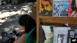 Un vendedor de libros callejero se entretiene en su teléfono inteligente, en La Habana, Cuba.