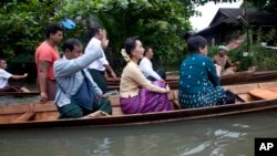  Myanmar opposition leader Aung San Suu Kyi, center, rides a boat on her way to a monastery where flood victims are sheltered, Monday, Aug. 3, 2015, in Bago, 80 kilometers (50 miles) northeast of Yangon, Myanmar. A report issued Saturday by the U.N. Offic