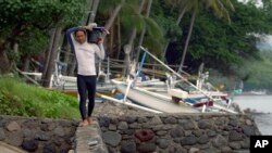Made Partiana walks along beach area at Les, Bali, Indonesia, April 11, 2021, as he prepares to catch aquarium fish.