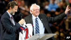 Democratic presidential candidate, Sen. Bernie Sanders, right, waves to the crowd after being presented with a shirt by Liberty President Jerry Falwell Jr., left, during a visit at Liberty University in Lynchburg, Virginia, Sept. 14, 2015.