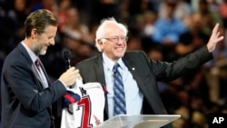 FILE - Democratic presidential candidate, Sen. Bernie Sanders, right, waves to the crowd after being presented with a shirt by Liberty President Jerry Falwell Jr., left, during a visit at Liberty University in Lynchburg, Virginia, Sept. 14, 2015.