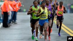 Lelisa Desisa, of Ethiopia, leads the pack past a water staion, in Natick, Mass., en route to a win in the Boston Marathon, April 20, 2015.