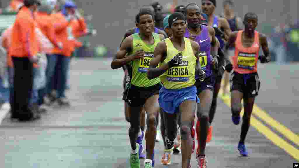 Lelisa Desisa, wa Ethiopia, anaongoza kundi la wenzake wakipita mbele ya kituo cha maji hapo Natick, Mass., akielekea kushinda mbio za Boston Marathon, April 20, 2015.