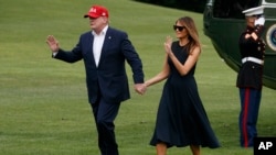 President Donald Trump and first lady Melania Trump hold hands and wave at supporters as they walk across the South Lawn on their return to the White House, June 7, 2019, in Washington.