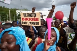 FILE - A man holds a sign reading "A transition led by the army" as supporters of the National Committee for the Salvation of the People take part in a rally on Independence Square in Bamako, Mali, Sept. 8, 2020.