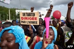 FILE - A man holds a sign reading "A transition led by the army" as supporters of the National Committee for the Salvation of the People take part in a rally on Independence Square in Bamako, Sept. 8, 2020.