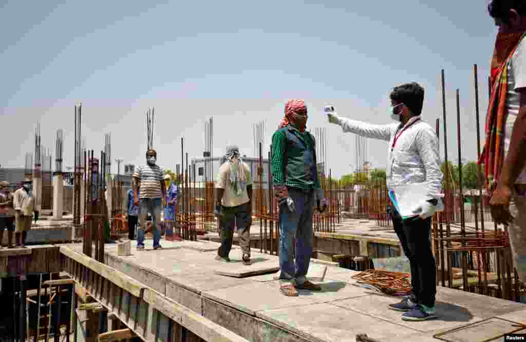 A health worker uses an infrared thermometer to measure the temperature of a worker at a building site in Ahmedabad, India.