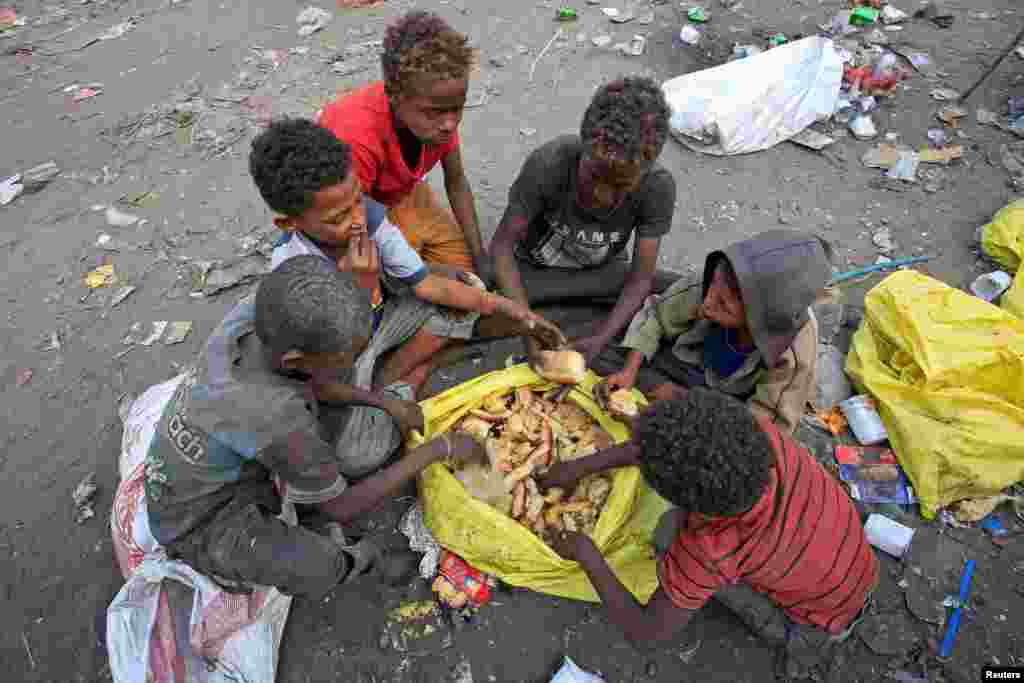 예멘 항구 도시 오데이다 외곽에서 남자 아이들이 쓰레기통 속에서 찾은 빵조각을 먹고 있다.