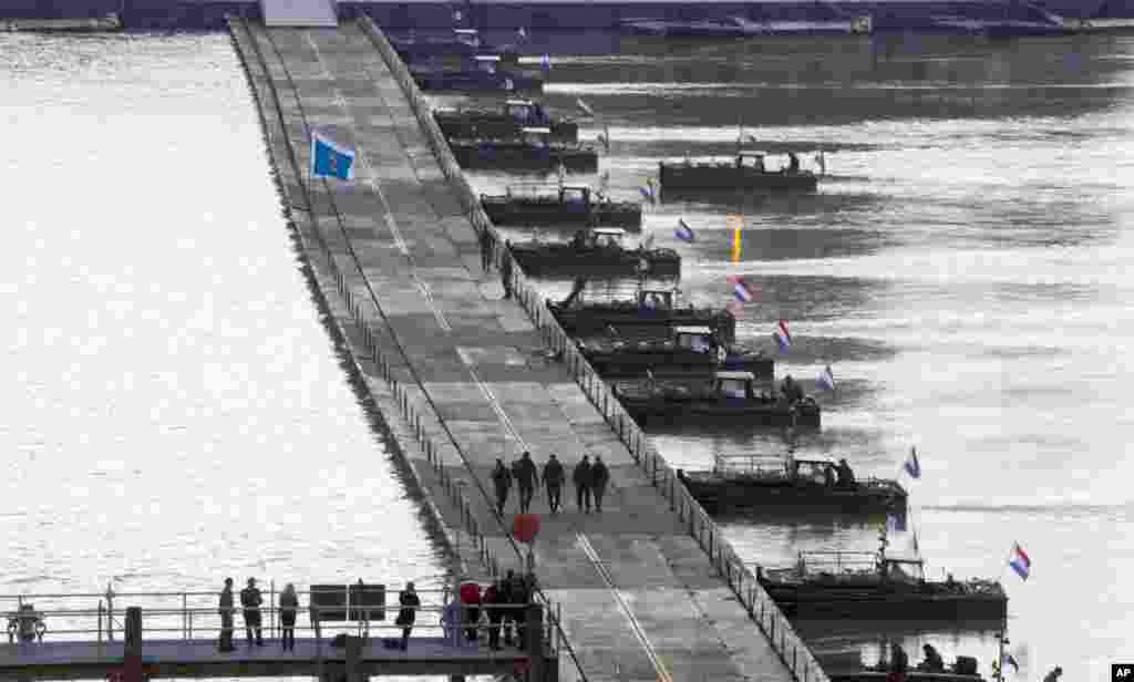 Belgian and Dutch army engineers walk across a completed floating pontoon bridge on the River Scheldt in Antwerp, Belgium. Antwerp will open it's World War I Centenary program in Oct. 2014 with the pontoon bridge and allow the general public to cross it. The pontoon bridge is an actual reconstruction of the original that spanned the River Scheldt at the start of the war in 1914 and played a major role in the defense of Antwerp.