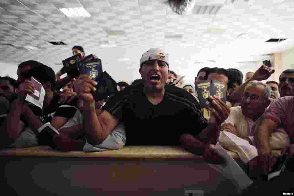 A man trying to cross into Egypt shouts as he holds his and other family members&#39; passports while he waits at the Rafah crossing between Egypt and the southern Gaza Strip, July 16, 2014.