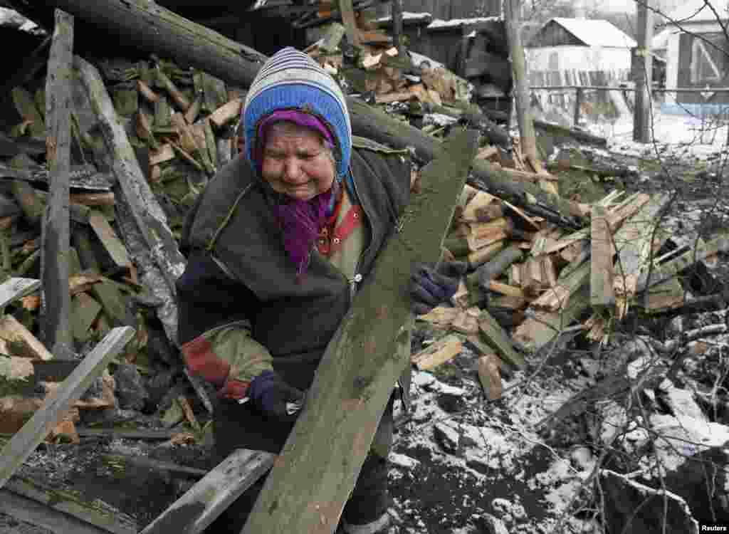 A woman reacts as she removes debris from her house damaged during fighting between pro-Russian rebels and Ukrainian government forces, in the town of Horlivka, eastern Ukraine, Feb. 10, 2015.