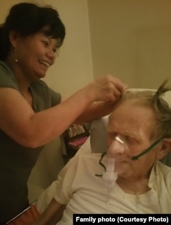 Nguyễn Thị Kim Nga, left, plays with Gary Wittig's hair while taking care of him in Riverdale, Georgia.