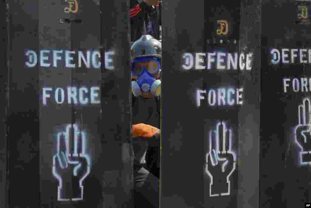 An anti-coup protester looks out from temporary barriers in Yangon, Myanmar.