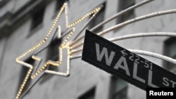 A holiday decoration is seen over Wall St. sign outside the New York Stock Exchange, November 27, 2012.