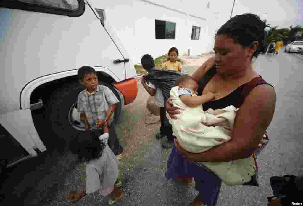 Una mujer y su hijo esperan para abordar el bus de evacuación mientras Ernesto se aproxima. El fenómeno metereológico se convirtió en un huracán el pasado martes, antes de llegar a México.