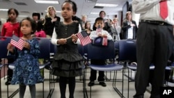 FILE- A pair of sisters adopted in Ethiopia hold flags as they listen to the singing of the national anthem at an adoption day ceremony in New York, Nov. 18, 2010.
