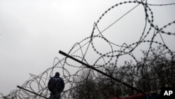 FILE - A Hungarian police officer stands guard at Serbia's border with Hungary near a makeshift camp for migrants in Horgos, Serbia, Feb. 8, 2017. 