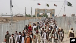 FILE - People cross the border coming from Afghanistan to Pakistan, at the border town of Chaman. Pakistan will reopen the Chaman border crossing for routine traffic on Sept. 1, 2016, after days of closure, officials said.