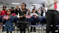 FILE - A pair of sisters adopted in Ethiopia hold flags as they listen to the singing of the national anthem at an adoption day ceremony in New York, Nov. 18, 2010.