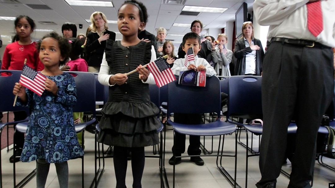 FILE- A pair of sisters adopted in Ethiopia hold flags as they listen to the singing of the national anthem at an adoption day ceremony in New York, Nov. 18, 2010.