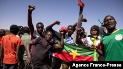People hold the Burkina Faso national flag as they gather at Nation square to support military in Ouagadougou on Jan. 24, 2022.