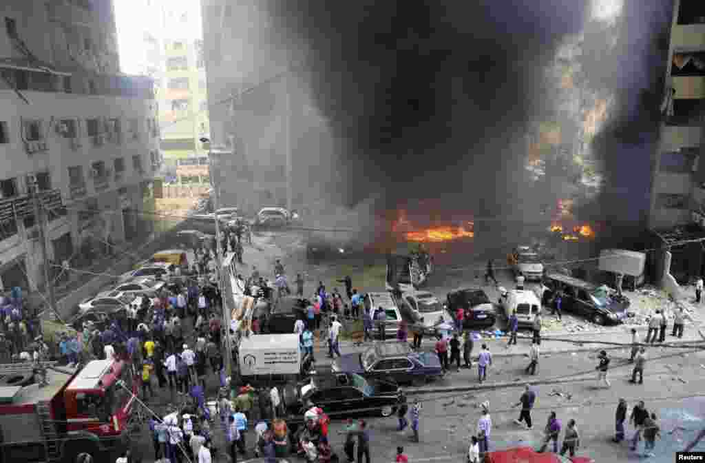 Civil Defense members, security personnel and civilians gather at the site of an explosion in Beirut's southern suburbs, July 9, 2013. 